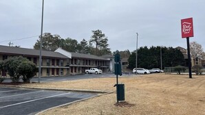 A Red Roof Inn with a parking lot, a building with a red roof, and a signboard. - Red Roof Inn Rockingham (Rockingham)