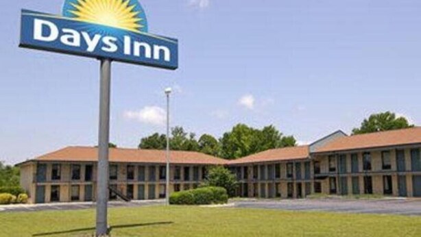 A Days Inn sign with a sun logo, indicating a hotel with a simple, functional design. - Red Roof Inn Rockingham (Rockingham)