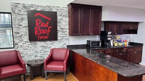 A Red Roof Inn kitchen with dark wood cabinets, a granite countertop, and a stone wall. - Red Roof Inn Rockingham (Rockingham)