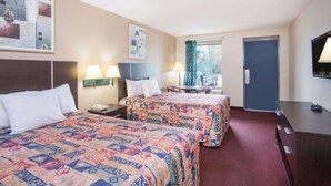 A hotel room with two beds, a desk, a chair, a TV, and a window with curtains. - Red Roof Inn Rockingham (Rockingham)