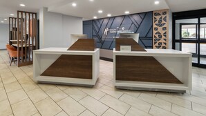 Ein Empfangsbereich mit zwei Theken, einem modernen Wanddesign und Blick durch eine Glastür.