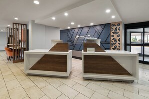 A reception area with two reception desks, a modern wall design, and a view through a glass door.