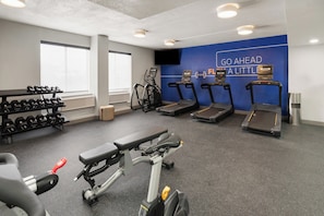 Una palestra con tapis roulant, manubri e una panca.