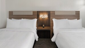 Ein Hotelzimmer mit zwei Betten, einem Nachttisch und einer Wandleuchte.