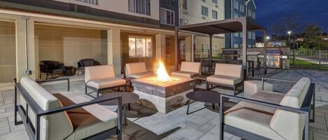 An outdoor patio with a fire pit, seating, and barbecue grills.