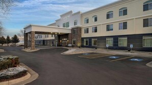 A hotel with a covered entrance, multiple windows, and parking spaces.