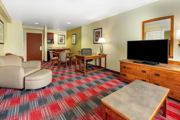 A hotel room with a large bed, a seating area with a table and chairs, a television, and a kitchenette. - Wingate by Wyndham Helena Airport (Helena)