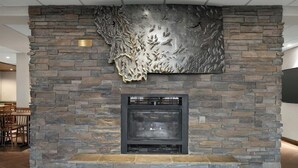 A stone fireplace with a metal art piece above it.