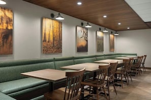 Ein Restaurant mit grünen Sitzbänken, Holztischen und -stühlen.