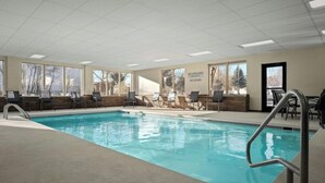 A swimming pool with chairs and a sign that reads "NO LIFEGUARD ON DUTY NO DIVING".