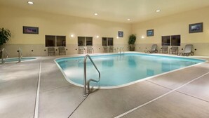 En stor inomhuspool med flera solstolar och ett mindre poolområde.