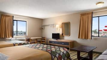 A hotel room with two beds, a desk, a TV, a mirror, and a view of the outside.