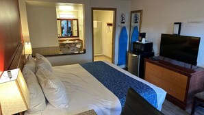 Ein Hotelzimmer mit einem Bett, einem Schreibtisch mit Computer, einem Fernseher und einem Duschbereich.