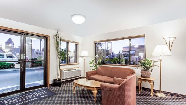 Eine Hotellobby mit einer Rezeption, einem braunen Sofa, einem Couchtisch und Topfpflanzen.