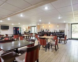 A spacious indoor dining area with multiple tables and chairs, a kitchen area, and a large window providing natural light.