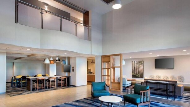A spacious lobby with a high ceiling, a mezzanine level, and a seating area with tables and chairs. - Fairfield by Marriott Inn & Suites Rome NY (Rome)