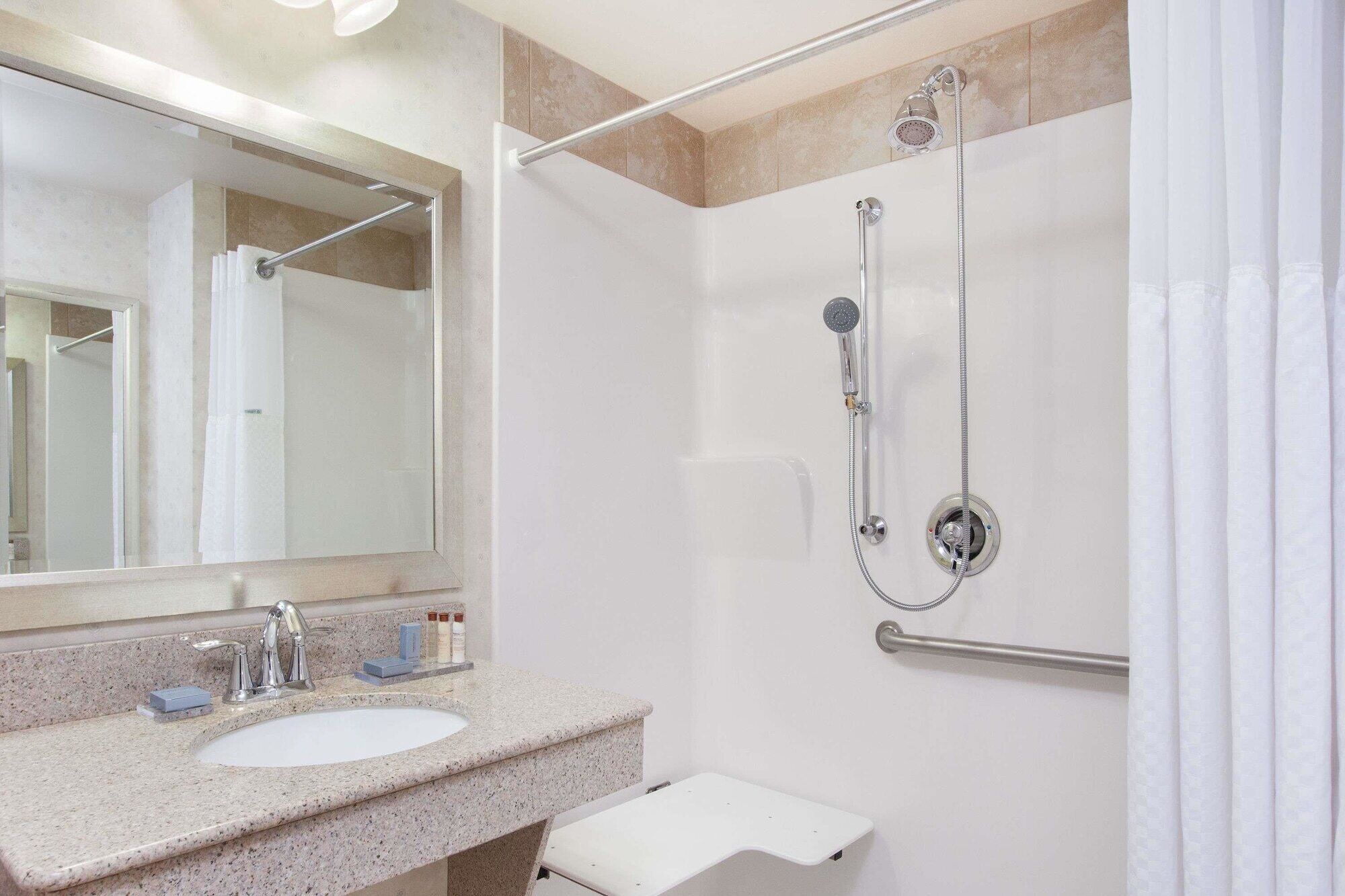 A bathroom with a sink, mirror, shower, and toilet.