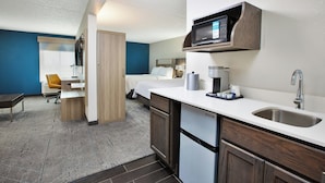 A compact hotel room with a kitchenette, a bed, a desk, and a chair. - Holiday Inn Express And Suite Eden Prairie Minneapolis (Eden Prairie)