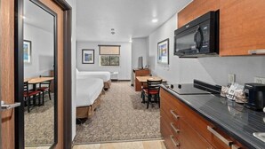 A compact hotel room with a kitchenette, a bed, a desk, and a chair. - Mainstay Suites Spokane Valley, WA (Spokane Valley)