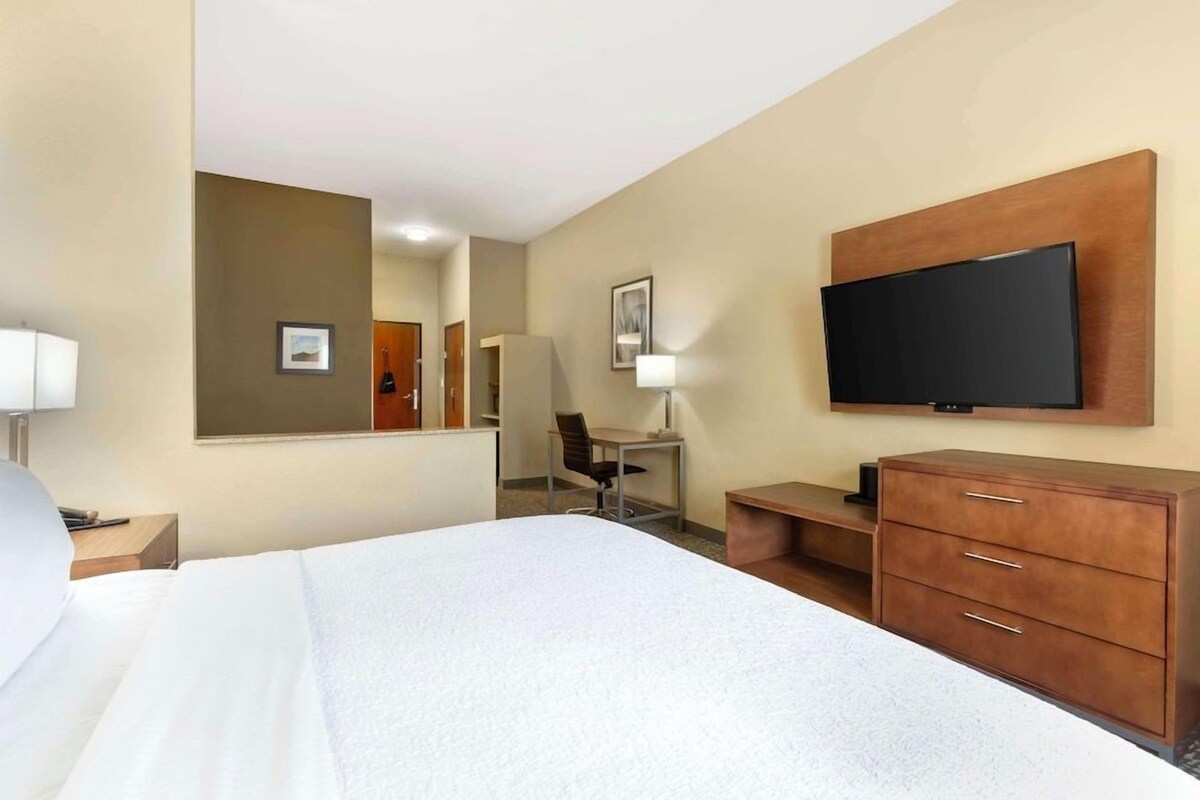 A hotel room with a bed, a desk, a chair, a television, and a wardrobe.
