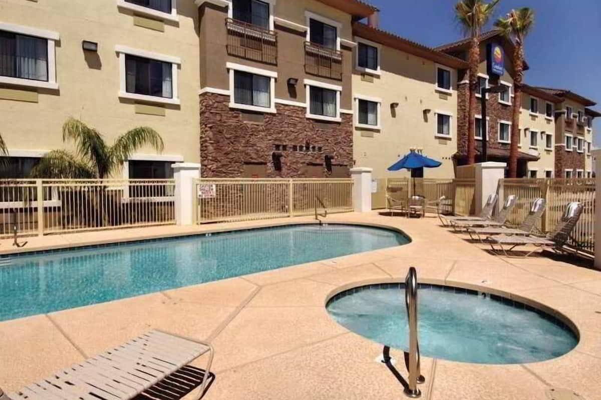 A hotel with a swimming pool, lounge chairs, and a stone wall.
