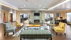 Un hall d’entrée spacieux avec une cheminée, des fauteuils confortables et un téléviseur fixé au mur.