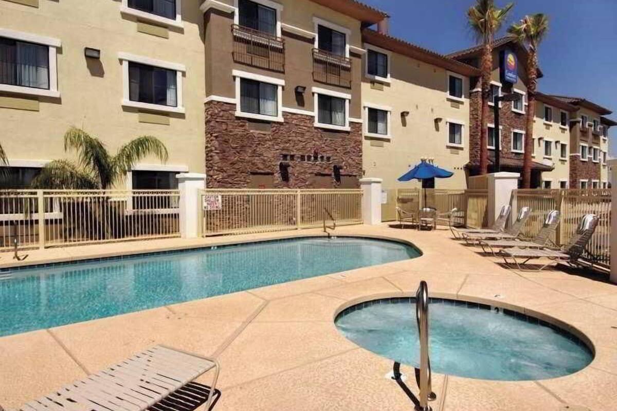 A hotel with a swimming pool, lounge chairs, and a hot tub.