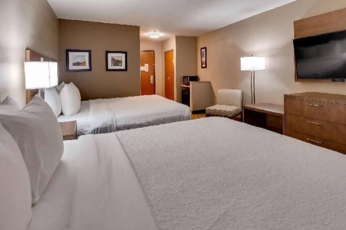 A hotel room with two beds, a TV, a desk, and a chair.