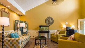 A living room with patterned sofas, a fish tank, and decorative wall art. - Red Roof Inn Jasper (Jasper)