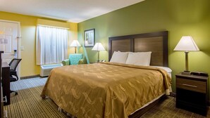 Habitación de hotel con una cama grande, dos lámparas de noche, un escritorio con silla y una ventana con cortinas.
