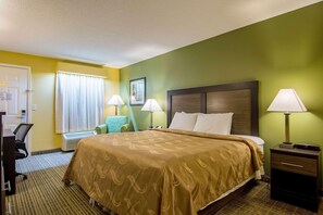 A hotel room with a large bed, two bedside lamps, a desk with a chair, and a window with curtains. - Red Roof Inn Jasper (Jasper)