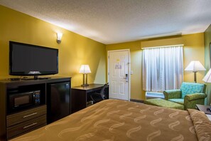 A hotel room with a bed, a desk with a computer, a TV, a microwave, a chair, and a door. - Red Roof Inn Jasper (Jasper)