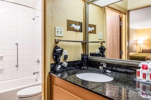 A bathroom with a bathtub, a sink with a mirror, and toiletries. - Econo Lodge Moss Point - Pascagoula (Moss Point)