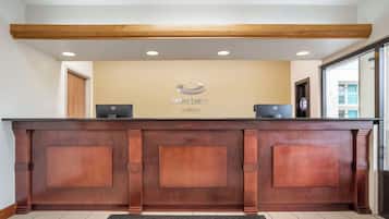 Un mostrador de recepción con detalles de madera, un logotipo en la parte superior y dos monitores de ordenador.