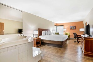 A hotel room with a large bed, a separate bathroom with a bathtub, a desk with a chair, and a television. - Econo Lodge Moss Point - Pascagoula (Moss Point)