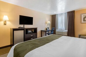 A hotel room with a bed, a desk, a television, a lamp, a chair, and a window with curtains. - Quality Inn & Suites Albuquerque North Near Balloon Fiesta Park (Albuquerque)