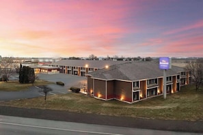 Een hotel met een modern design, met een parkeerplaats en een groot gebouw met meerdere verdiepingen.