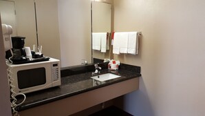 Une salle de bain d’hôtel équipée d’un four à micro-ondes encastré, d’un lavabo et d’un porte-serviettes.