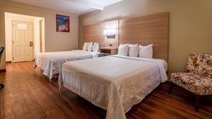 Une chambre d’hôtel avec deux lits, une tête de lit en bois, une table de chevet, une chaise et une porte.