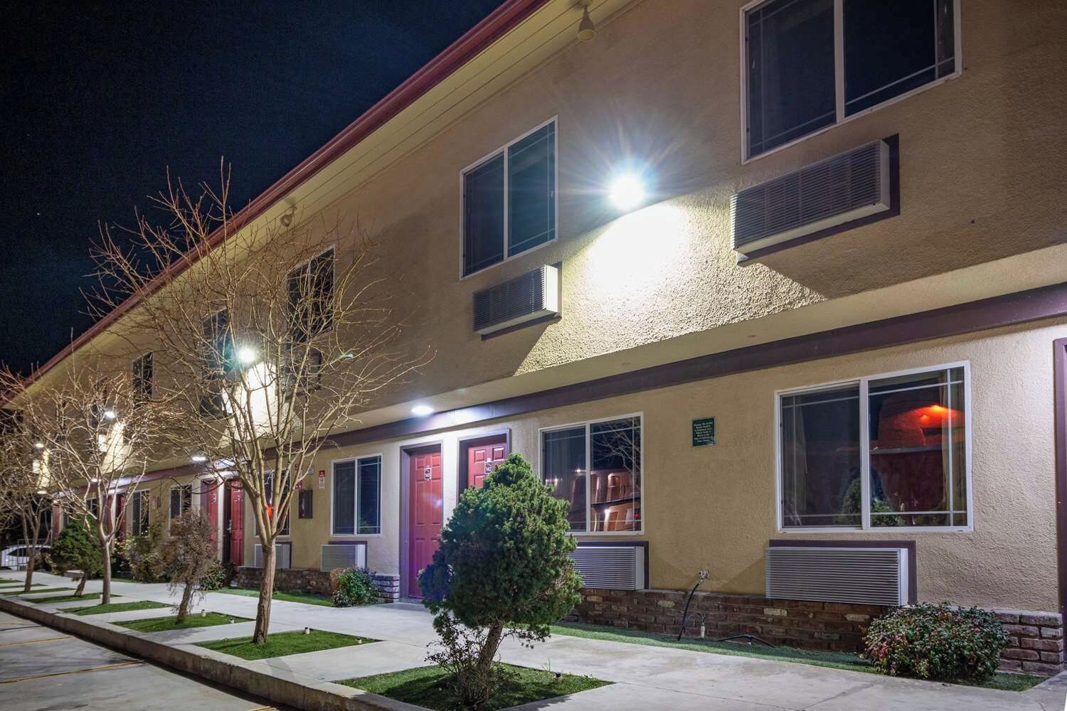 A multi-story building with a row of windows, a door, and a small tree in the foreground.