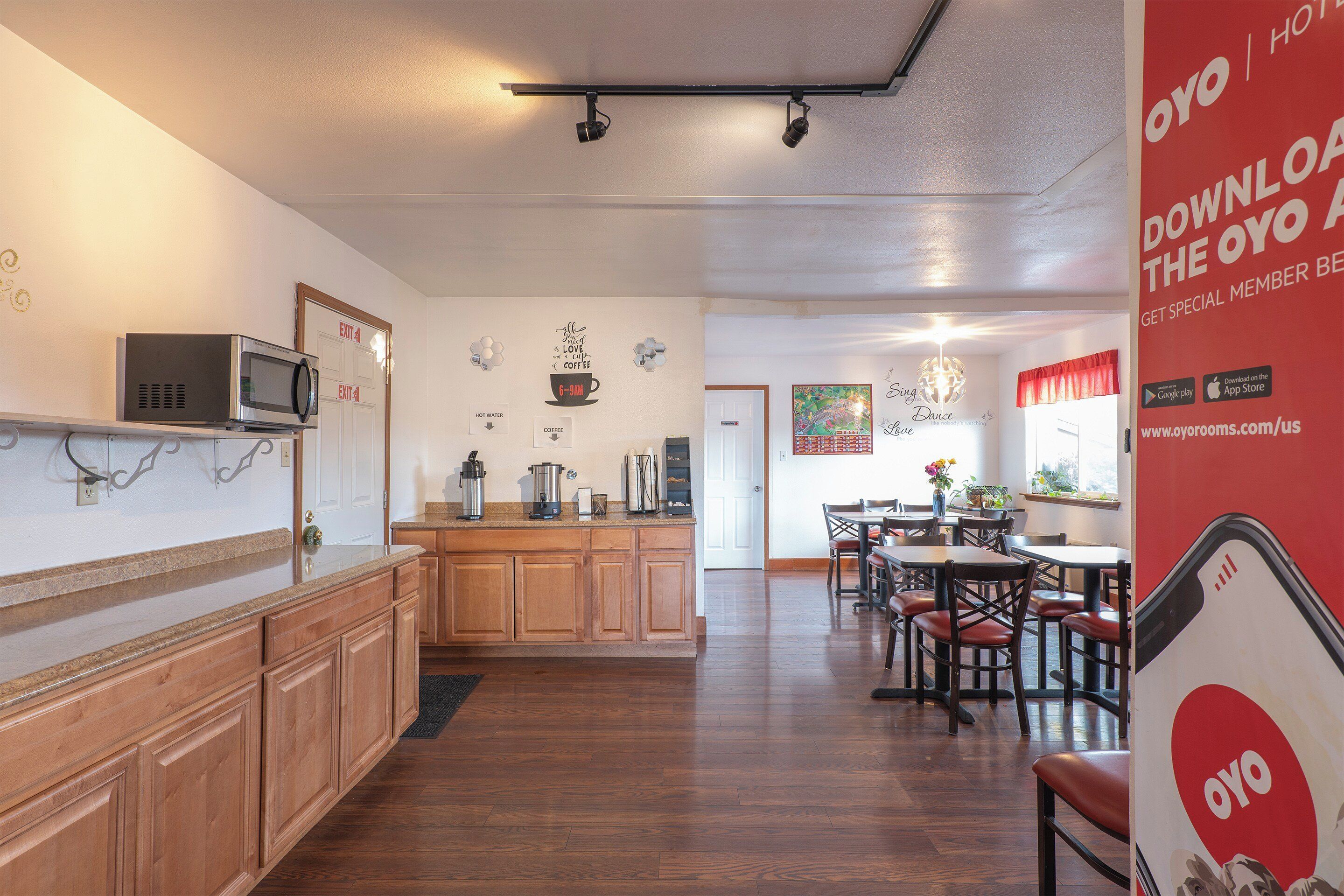 Una cocina de hotel con armarios de madera, un microondas y una estación de café.
