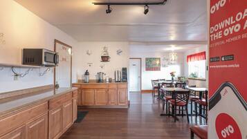 Una cocina de hotel con armarios de madera, un microondas y una estación de café.