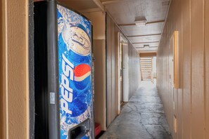 A hallway with a vending machine on the left, doors on the right, and a concrete floor. - Travelodge by Wyndham Chehalis (Chehalis)