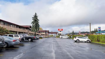 A hotel with a red sign, a parking lot with cars, and a gas station in the background.