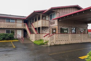 A two-story motel with a red and beige color scheme, a covered outdoor area, and a parking lot. - Travelodge by Wyndham Chehalis (Chehalis)