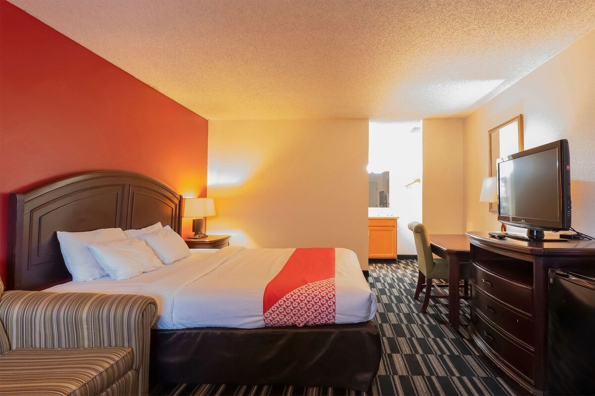 A hotel room with a bed, a desk, a television, and a chair.