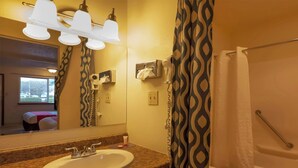 Une salle de bain équipée d’un lavabo, d’un miroir, d’un porte-serviettes et d’un rideau de douche.