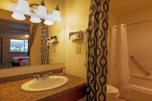 Un baño con lavamanos, espejo, toallero y cortina de ducha.