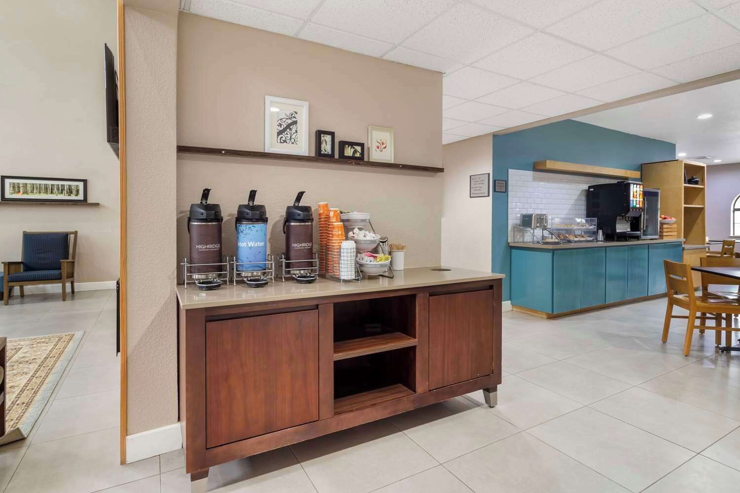 A hotel lobby with a reception desk, a coffee station, and a dining area.