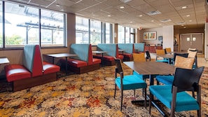 A hotel dining area with booths and tables, large windows, and a patterned carpet. - Radisson Hotel St. Paul Downtown (St. Paul)